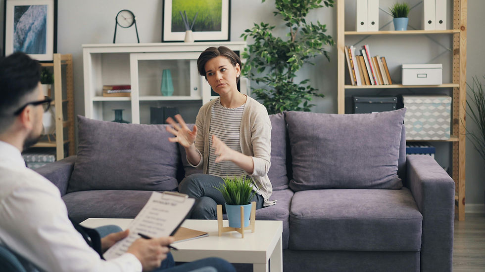 Woman gesturing during therapy session with a therapist and notes on the couch.