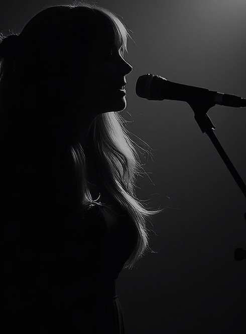 dark themed with a man (silhoutee) playing a guitar in a studio and a woman (silhoutte) si