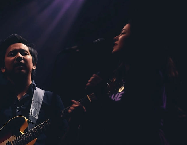 dark themed image with hint of color of man (indian features sillouhette) on guitar with w