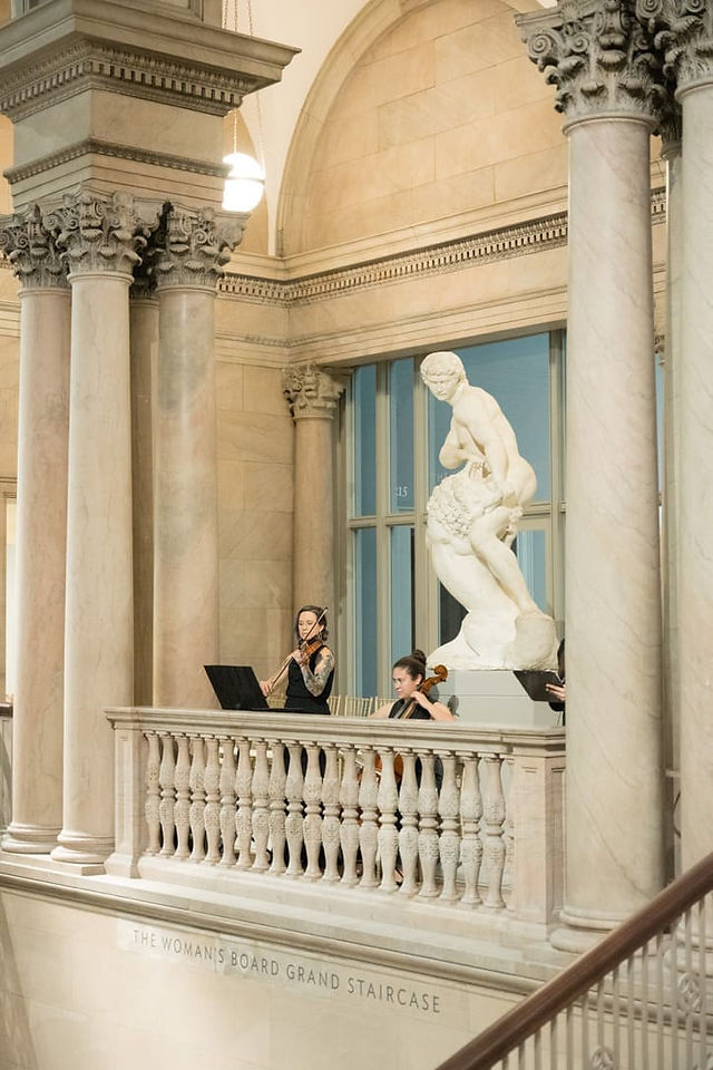 Musicians next to a marble statute