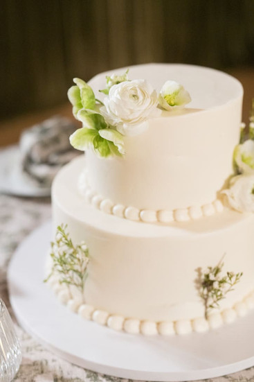 White wedding cake with soft white flowers and subtle greenery