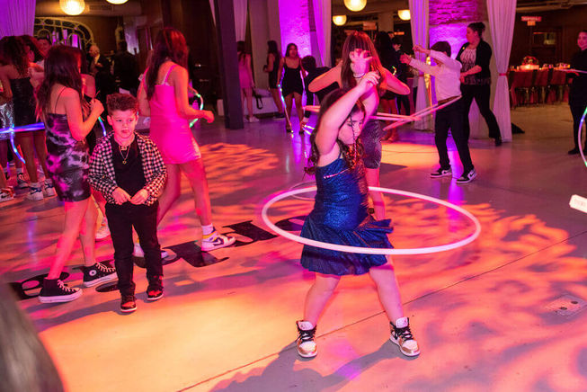 A guest hula-hooping on the dance floor, with other attendees joining in the fun.