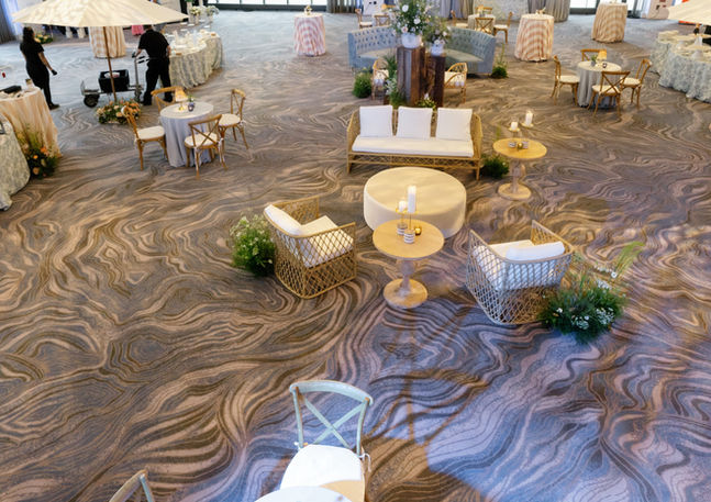 Aerial view of the Radisson Blu Aqua Hotel Chicago Atlantic Ballroom during a Wedicity reception event, showing the full room layout with lounge seating clusters, round tables, floor-to-ceiling windows, and the venue's distinctive marbled carpet.