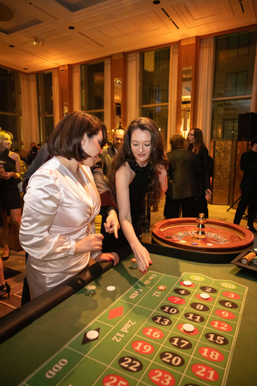 Two women in formal attire placing casino chips on a roulette table layout at a Chicago casino night event
