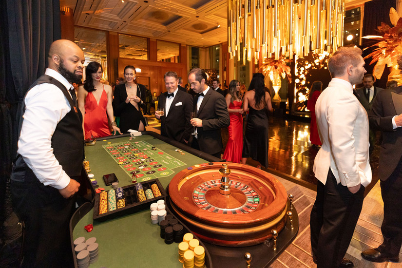 Professional dealer at a roulette table rental with formally dressed guests at a casino night gala in Chicago