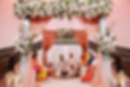 A beautifully decorated mandap with floral arrangements and draped fabric, hosting a traditional Indian wedding ceremony.