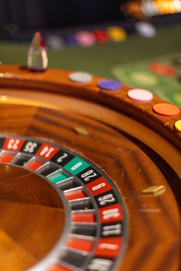Extreme close-up of a roulette wheel showing red and black numbered pockets with casino chips visible on the green felt in the background