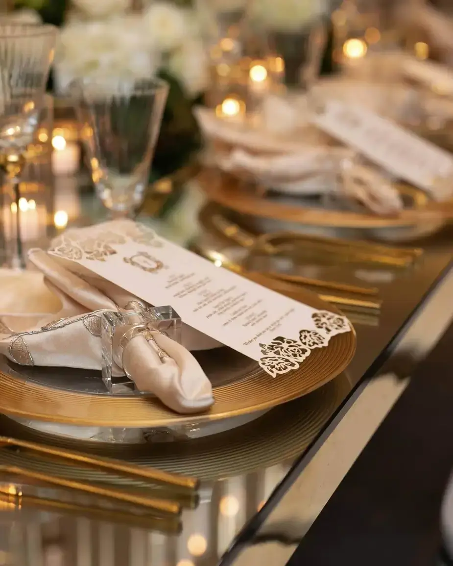 Closeup of a place setting with a gold charger, soft gold napkin, a and dye cut menu