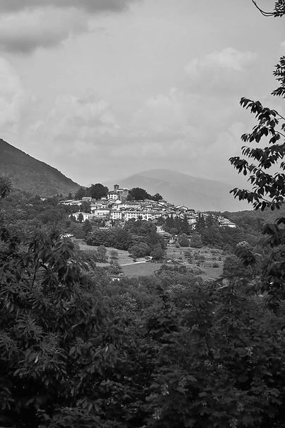 Dorf auf einem Hügel, umgeben von Bäumen, in Schwarzweißfotografie, Yoga Retreat Tessin.