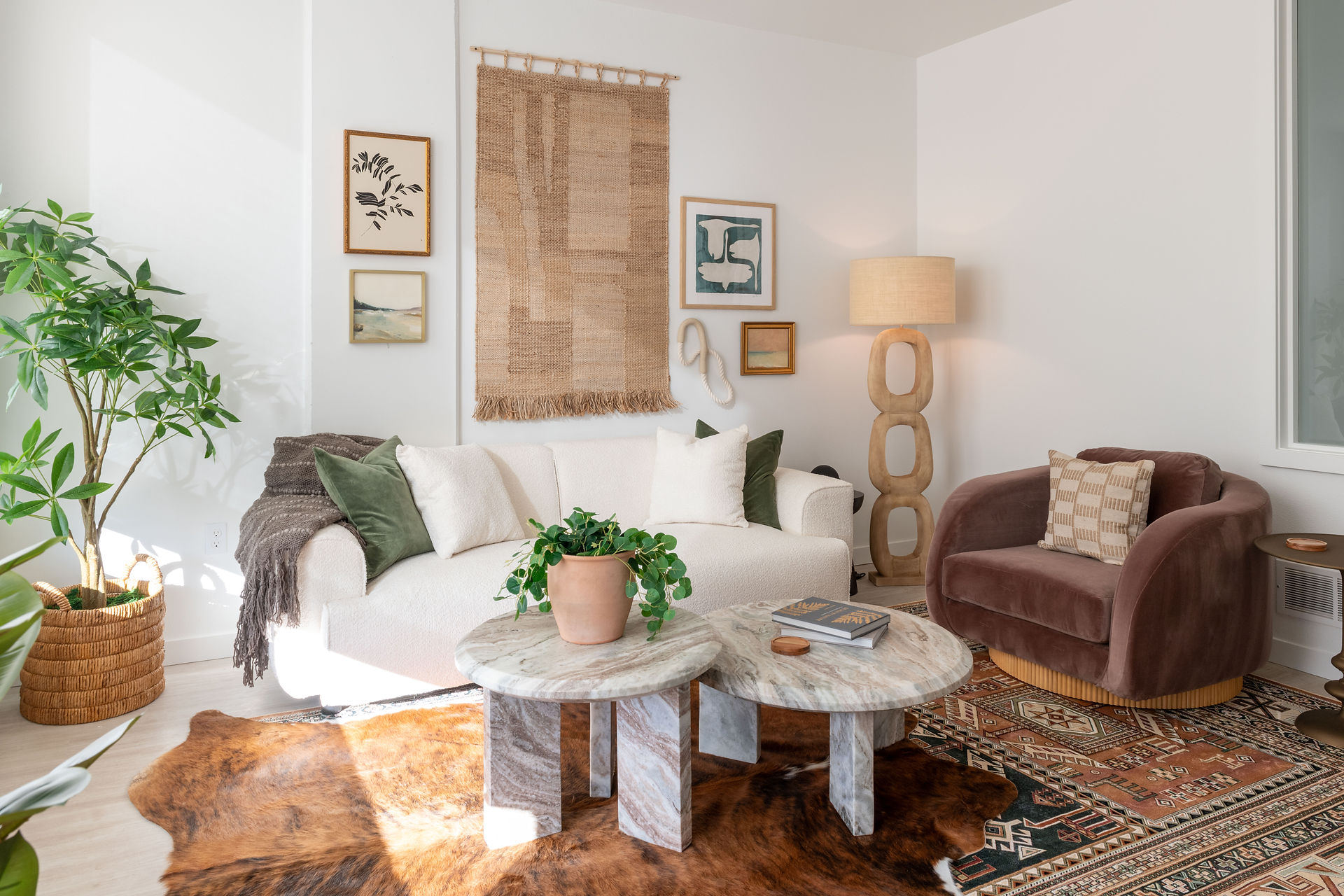 Swell Apartments, model unit living room with layered rugs, marble tables, artwork, and plants