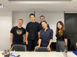 Group photo of diverse people smiling in a bright classroom setting.