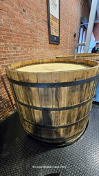 A circular wooden fermentation vat made of light-colored oak staves at Michter's Distillery. Metal hoops tightly bind the vertical staves together, showing the impressive scale of the distillery's equipment.
