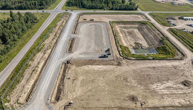Aerial view of a graded industrial site with open land beside a warehouse pad
