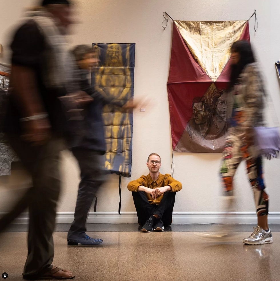 Jason Leith seated next to his artwork showcased at The Grove Center in 2019. Photo courtesy of Jason Leith, Sacred Streets
