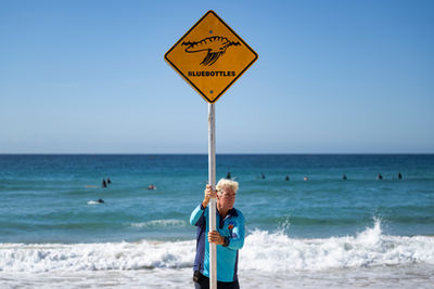 A lifestyle photo of a Bondi Rescue lifeguard erecting a sign on the beach  in Bondi Sydney Australia