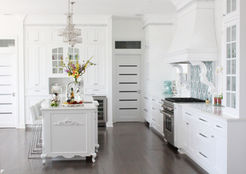 Devon Rose Interiors design a large white kitchen with a large island and a living room