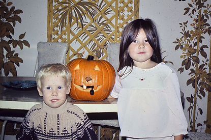 an image of a little boy and little girl with a pumpkin on a table in the background