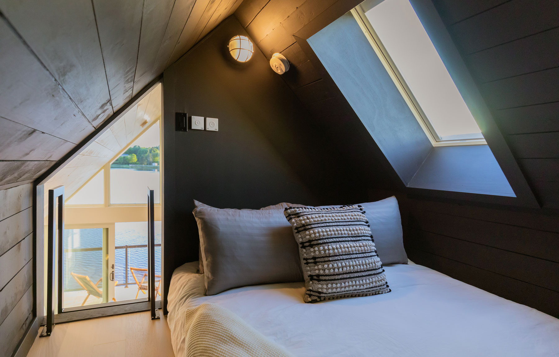 Modern architecture bedroom loft with skylights with black horizontal wood boards in Nova Scotia designed by Nicholas Fudge Architects.