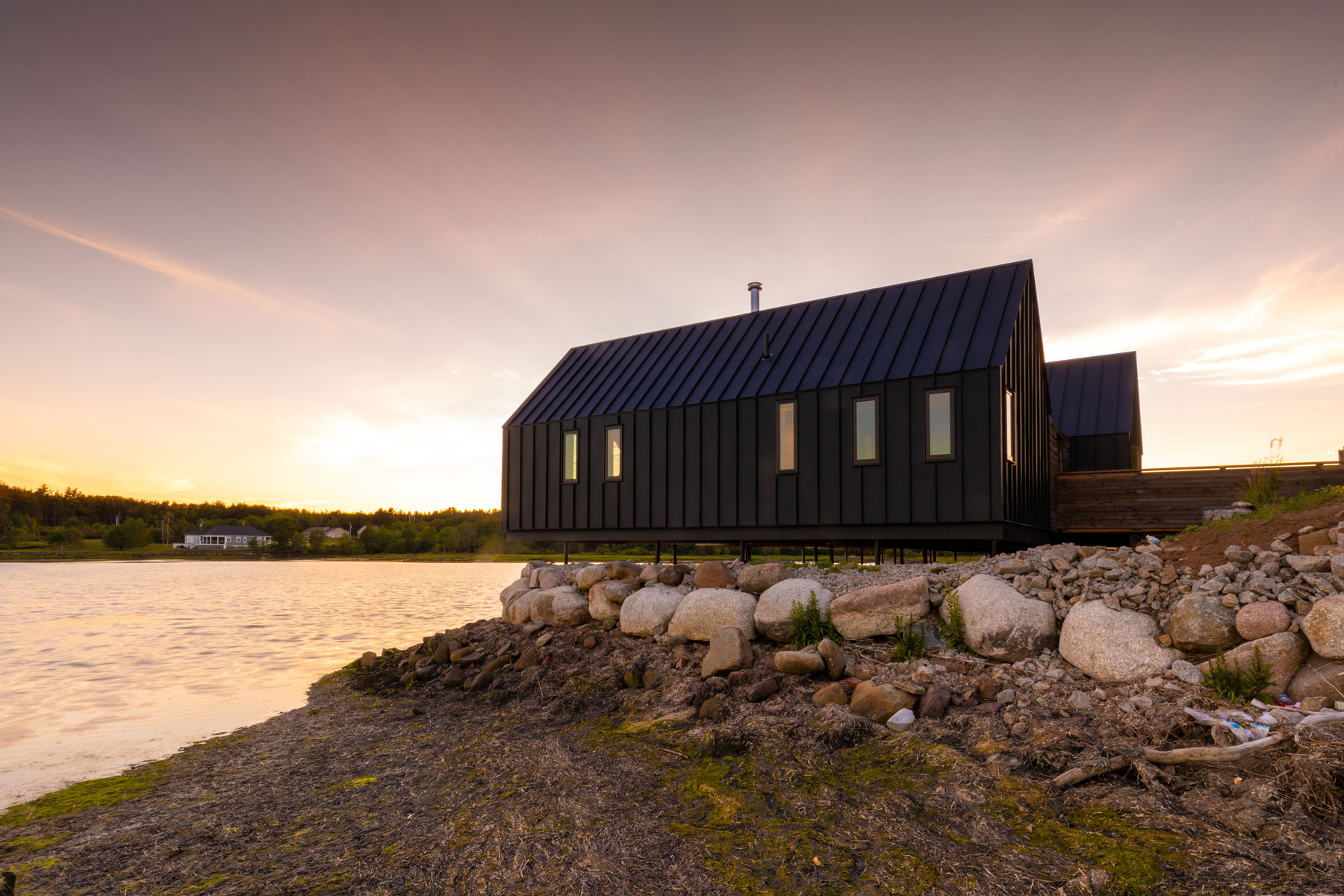 Modern architecture house with standing seam metal roof on stilts located in South Cove, Nova Scotia designed by Nicholas Fudge Architects.