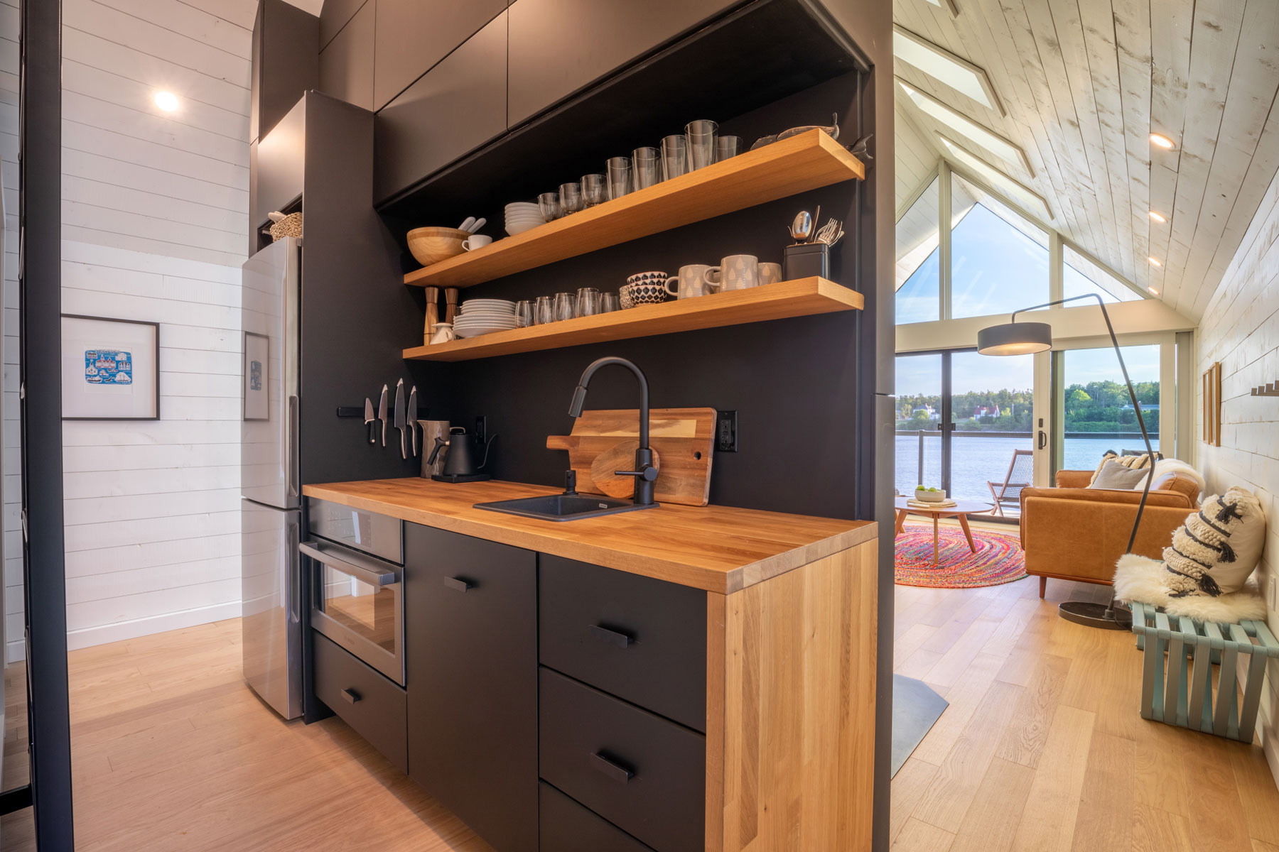 Modern architecture kitchenette with black cabinetry and wood shelves and butcherblock designed by Nicholas Fudge Architects.