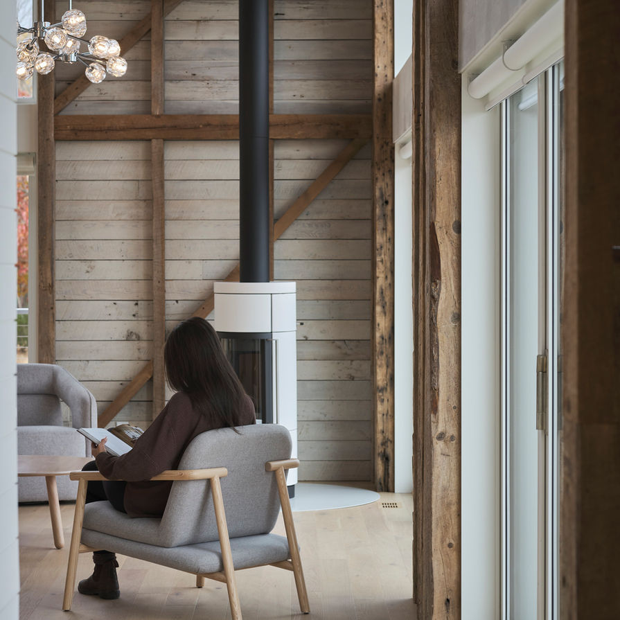 Modern rustic barn house interior with wood stove located in Nova Scotia designed by Nicholas Fudge Architects.