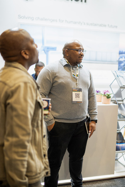 Corporate networking event photography: Two men talking at an exhibition stand, captured by an event photographer in Cape Town.