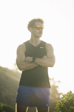 Male athlete standing portrait in golden hour sunlight on Cape Town mountain terrain wearing athletic gear – sports photographer Cape Town