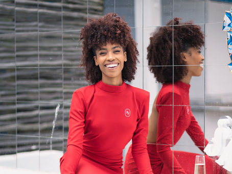 Model in a red outfit smiling in front of a mirrored wall during a vibrant personal branding photoshoot in Cape Town