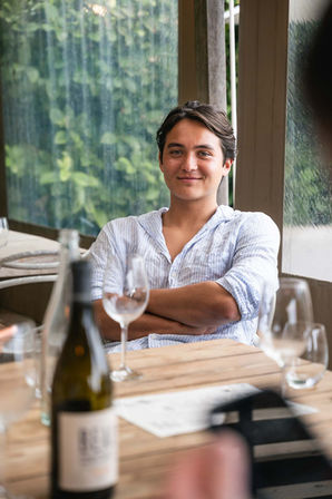 Man seated at outdoor wine event table with wine glasses and bottles – event photographer Cape Town