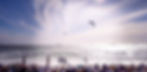 Crowd at a beach watching water sports athletes with custom earplugs – designed for surfers, swimmers, and kitesurfers seeking lifetime ear protection.