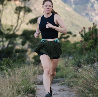 Dynamic full-body shot of a runner mid-stride on a rocky path, showcasing trail running photographer Cape Town work.