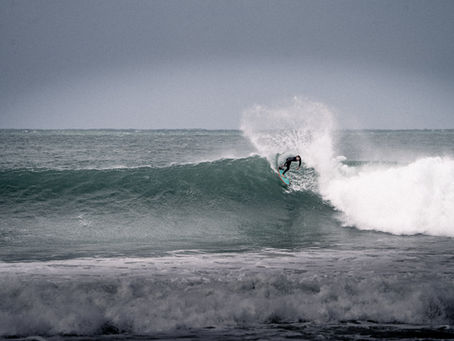 Surfer performing a top turn on a wave while wearing IARS custom-fit earplugs for water protection.