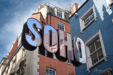 reflective SOHO sign hanging over the street in London
