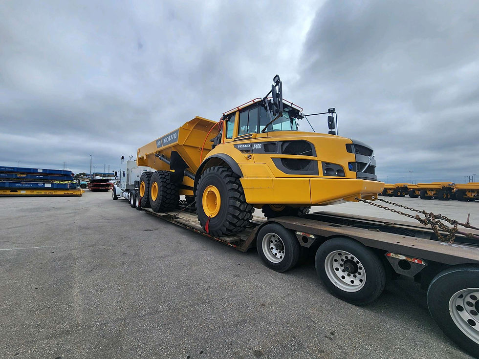 White semi hauling a cat dump truck on a double drop trailer.