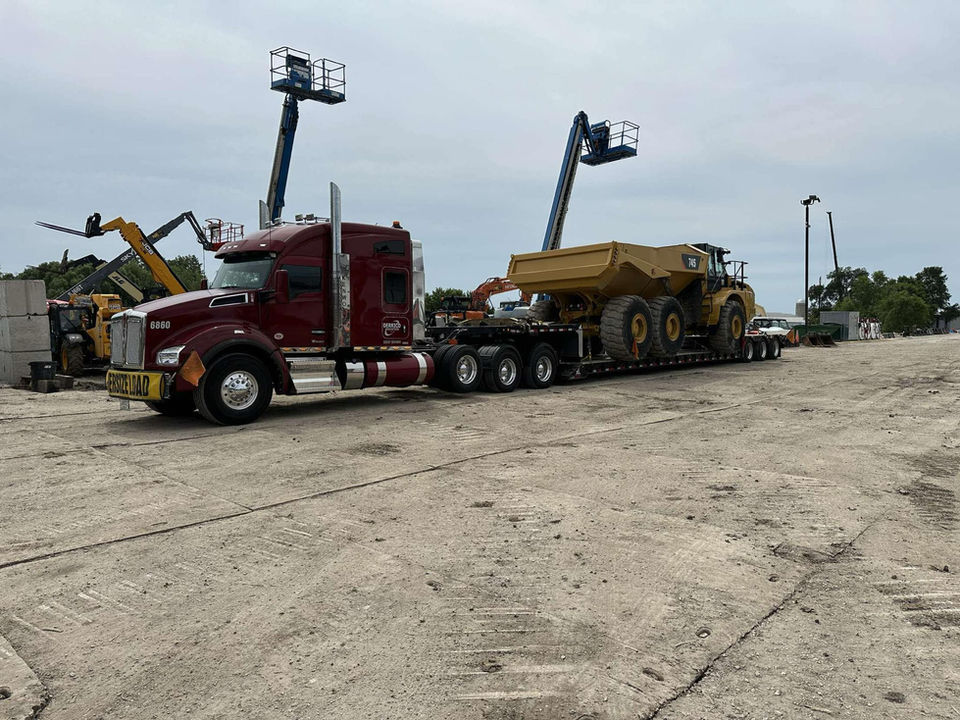 Maroon semi hauling a Caterpillar dump truck.