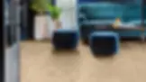 Blue sofa and ottomans in a living room with wood effect Polyflor Expona LVT flooring. White planters with green plants are near a window, creating a cozy vibe.