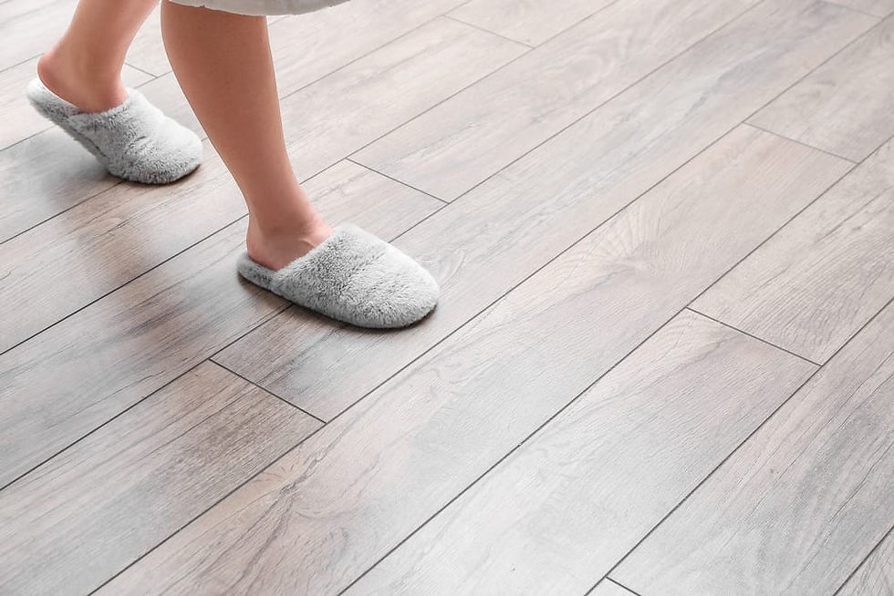 Feet in gray fluffy slippers walk on light luxury vinyl flooring. The scene has a cozy, calm vibe. Squeeky floor.