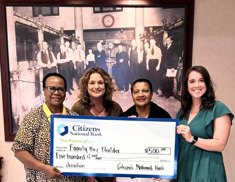 Four people smiling and holding a large $500 check from Citizens National Bank for "Family Biz Builder." A vintage photo is in the background.