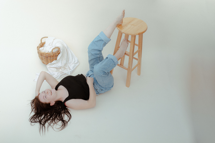 Person seated on stool, editorial wedding photography and film photographer style, capturing personality and casual luxury aesthetic.