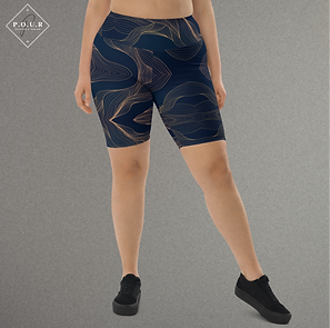 Person wearing navy and gold swirl-patterned biker shorts paired with black sneakers.