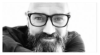 A an image of Dave Steele looking at the camera with his glasses on and smiling at the camera.