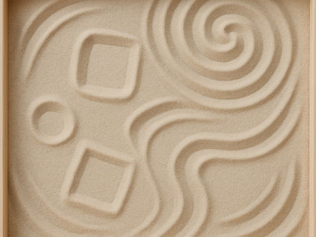 An abstract close-up image of a rectangular sandbox. The sand is gently textured with soft ripples, swirls, and a few simple geometric shapes drawn into the surface—suggesting imaginative play and open-ended exploration. The scene is calm and minimal, evoking a sense of curiosity, creativity, and therapeutic presence.