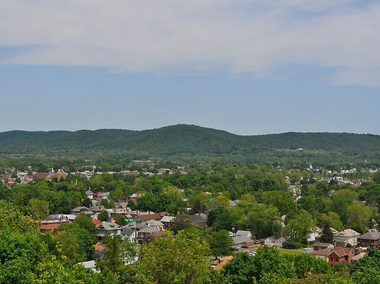 A drone-view of appalachian Southeast Ohio, showing green, rolling hills and buildings among them.