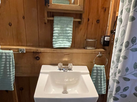 A simple pedestal sink is paired with a mirrored medicine cabinet, hairdryer and convenient towel bars, keeping essentials within easy reach.