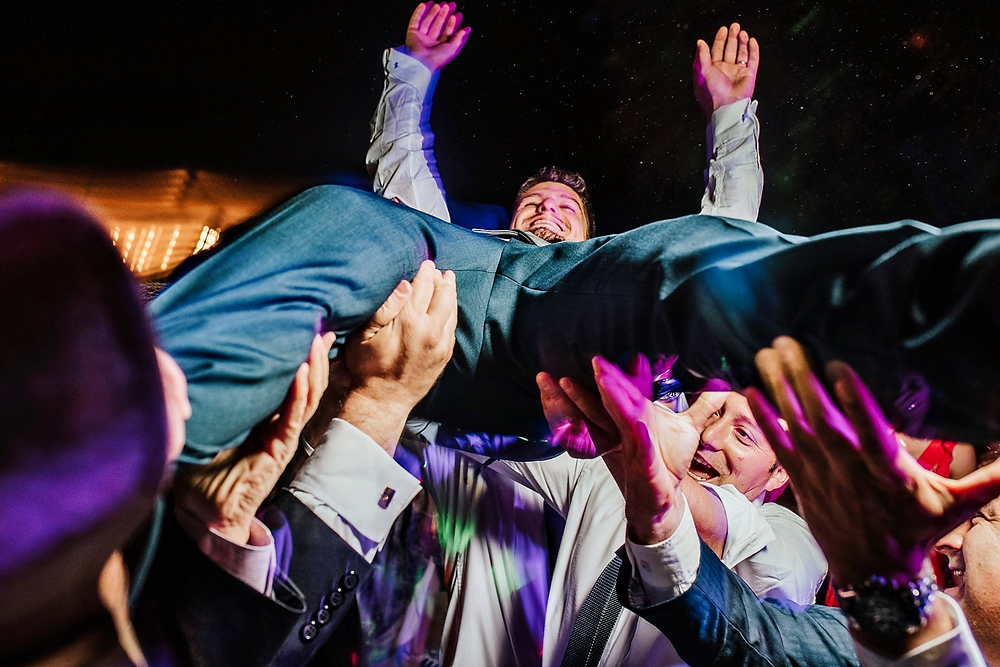 Hombre en traje siendo levantado en celebración.
