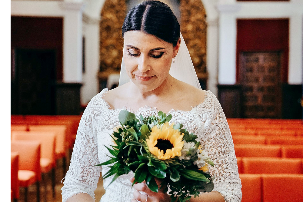 Novia en vestido de encaje blanco con ramo de girasoles