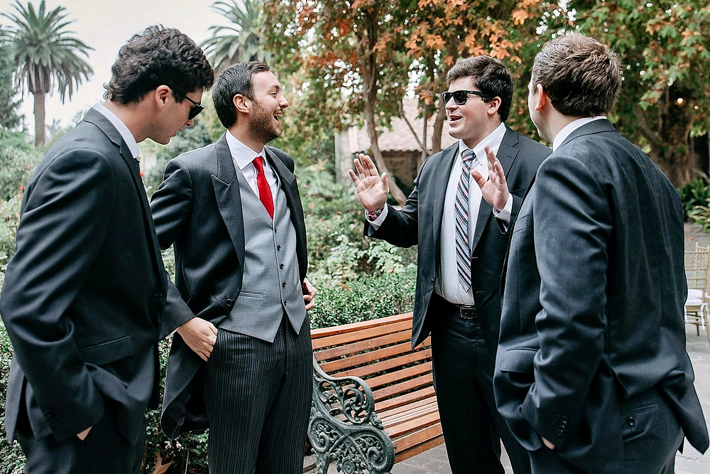 Cuatro hombres de traje hablando en la boda de Irene y Jose.