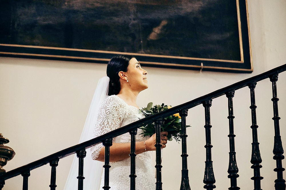 Novia con vestido de encaje y ramo subiendo escalera