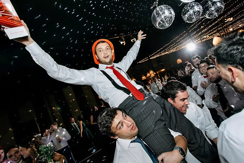 Hombre con sombrero naranja a hombros en la boda de Irene y Jose.