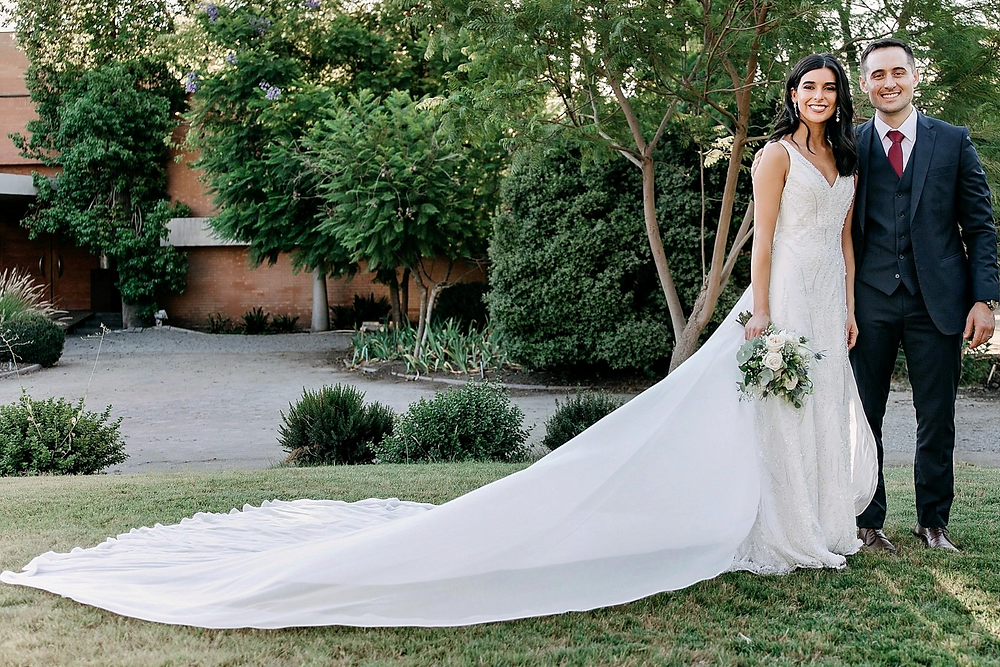 Alejandro y Marina, novios en su boda, posan al aire libre.